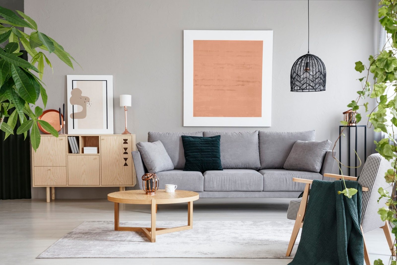 pink poster above grey sofa in living room interior with wooden e1647337548571