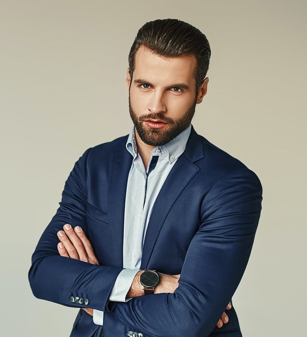 portrait of a charming young businessman dressed in suit posing while standing and looking at camera e1647409752188