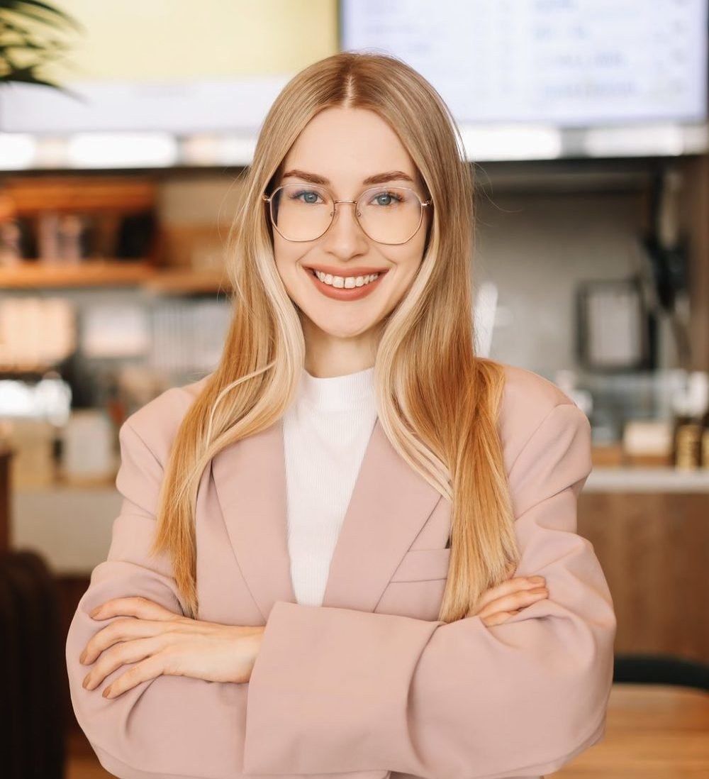 portrait of a smiling business woman with glasses cafe hostess looking into the camera e1647497875647