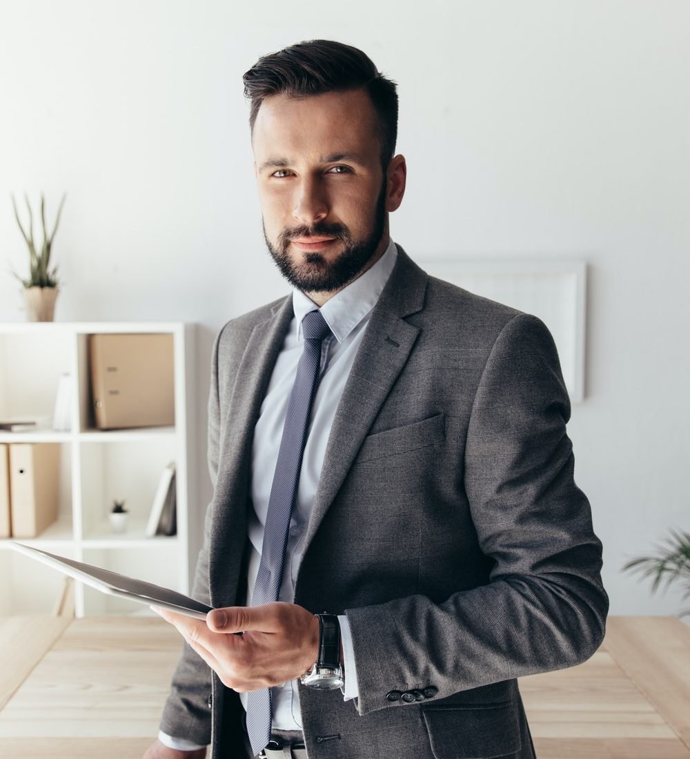 portrait of smiling businessman with digital tablet looking at camera e1647409504625
