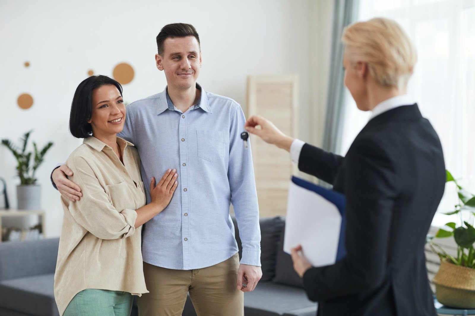 realtor giving the keys to young couple e1647506867804